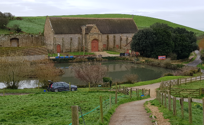 Large stone building opposite a small lake in Abbotsbury